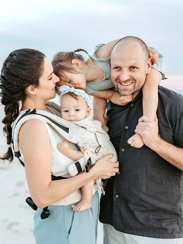 Fotografía de un familia feliz porteando con mochila ergonómica quokkababy e-carrier